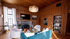 A living room with a fireplace, a television, a sofa, and a chandelier. - Doc's Place | Historic Jewel In Downtown Flagstaff | Sophisticated Elegance (Flagstaff)