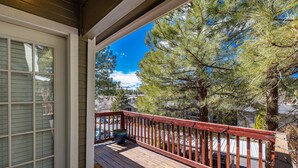 A wooden deck with a red railing, a large window, and a view of pine trees and houses. - Mountain Jewel | Modern Townhome in the Pines | Great Location | Near Downtown Flagstaff (Flagstaff)