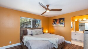A bedroom with a bed, a ceiling fan, a window, and a bathroom with a sink and mirror. - Mountain Jewel | Modern Townhome in the Pines | Great Location | Near Downtown Flagstaff (Flagstaff)