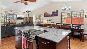 A spacious kitchen with a central island, wooden dining table, and chairs. - Eternal Treehouse | Hot Tub, Outdoor Paradise, Entertainment & Scenic Pine Views (Flagstaff)