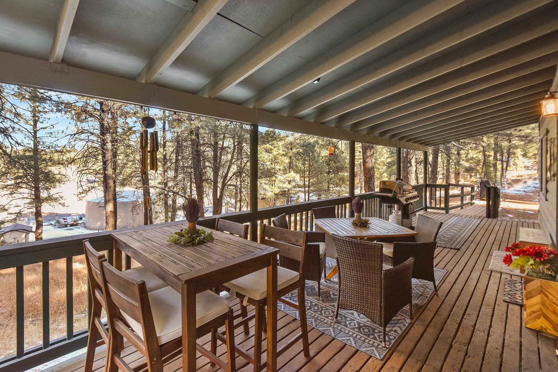 Una terraza techada al aire libre con mobiliario de madera y una parrilla.
