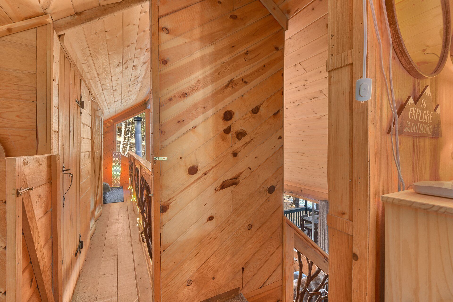 Un interior de madera con techo inclinado, una escalera a la vista y un letrero que dice "GO EXPLORE THE GREAT OUTDOORS".