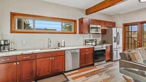 A modern kitchen with wooden cabinets, stainless steel appliances, and a large window.