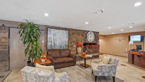A lobby with a stone wall, a large clock, a fireplace, and a reception desk.