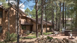 A cabin with a stone wall, outdoor seating, and a stone fireplace. - Burning Tree Lodge - Forest Views, Fire Pit, AC | Pet and Family Friendly (Flagstaff)