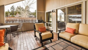 Un espacio de estar techado al aire libre con suelo de madera, una mesa y sillas.