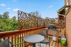 Enjoy a balcony with a lush view, featuring a table for two, barbecue grill, and comfortable seating.