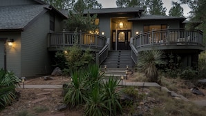 A two-story house with a central staircase, a balcony, and a well-maintained garden with various plants.