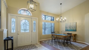 A dining area with a wooden table and chairs, a chandelier, and a painting on the wall.