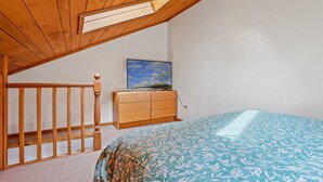 A bedroom with a wooden ceiling, a bed with a patterned bedspread, a wooden dresser, and a TV on the dresser. - Hummingbird Haven | Pet-Friendly Casita | Cozy Gas Fireplace | Close to Downtown (Flagstaff)