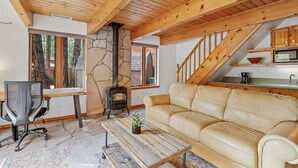 A cozy living room with a stone fireplace, a sofa, a coffee table, and a TV. - Hummingbird Haven | Pet-Friendly Casita | Cozy Gas Fireplace | Close to Downtown (Flagstaff)