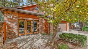 A two-story house with a brick facade, a garage, and a well-maintained front yard with a tree and shrubs. - Hummingbird Haven | Pet-Friendly Casita | Cozy Gas Fireplace | Close to Downtown (Flagstaff)