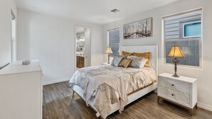 A bedroom with a large bed, bedside tables, a dresser, and a window with blinds. - Our Happy Place | Minutes to Downtown & NAU | Brand New Home (Flagstaff)