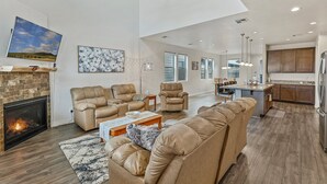 A spacious living room with a fireplace, leather sofas, and a large TV. - Our Happy Place | Minutes to Downtown & NAU | Brand New Home (Flagstaff)