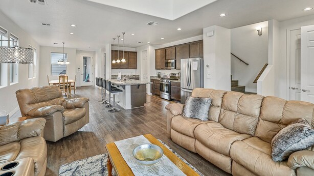 A spacious living room with a leather sofa, a coffee table, and a dining area in the background. - Our Happy Place | Minutes to Downtown & NAU | Brand New Home (Flagstaff)