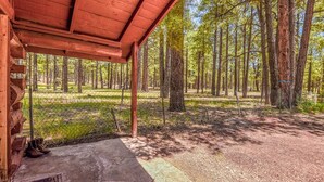 A wooden cabin with a porch overlooking a forested area.