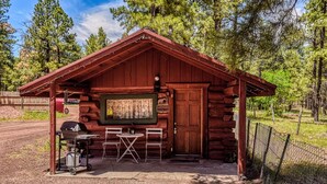 A rustic cabin with a wooden exterior, a small porch area with a grill, and a door marked with the number 2.