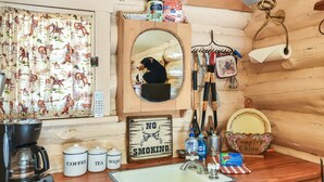 A rustic kitchen with a coffee maker, tea and sugar containers, a mirror, and a 'No Smoking' sign.