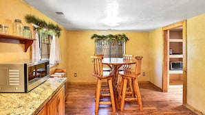 A kitchen with a wooden table, granite countertop, and a microwave. - Rustic Star | Authentic Log Cabin in the Woods | Near the Grand Canyon, Flagstaff & Williams (Bellemont)