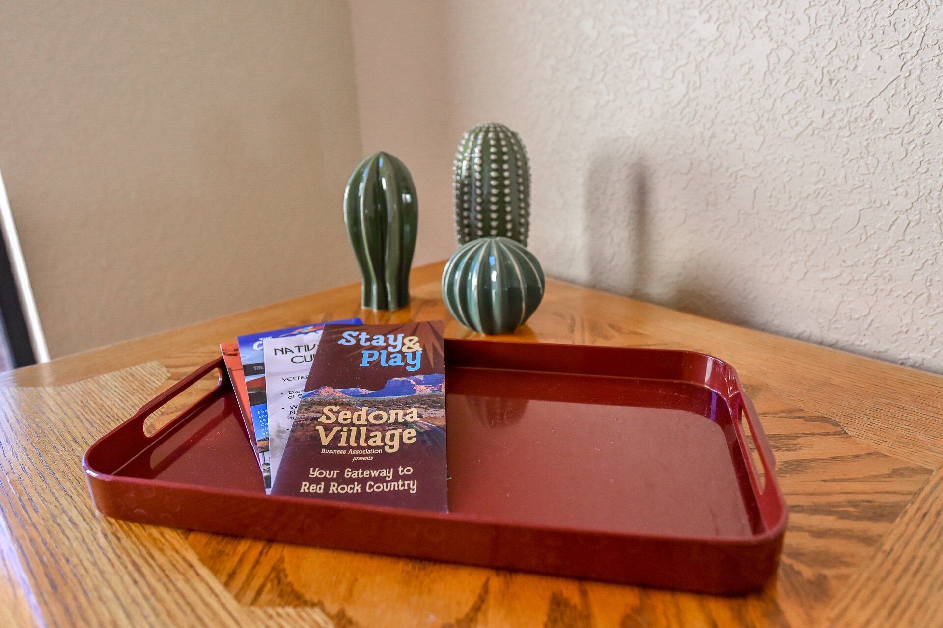 Een dienblad met een brochure met de titel 'Sedona Village' en twee decoratieve vazen op een houten tafel.