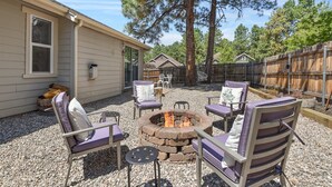 A patio area with outdoor furniture, a fire pit, and a wooden fence. - Take Me To The Mountains | Game Room | Fire Pit | Fenced Yard | Dog Friendly (Flagstaff)