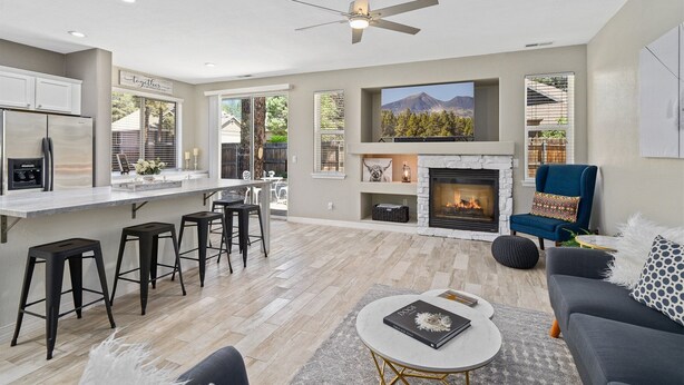 A modern kitchen with a built-in island, a dining area with bar stools, a fireplace, and a seating area with a sofa and chairs. - Take Me To The Mountains | Game Room | Fire Pit | Fenced Yard | Dog Friendly (Flagstaff)