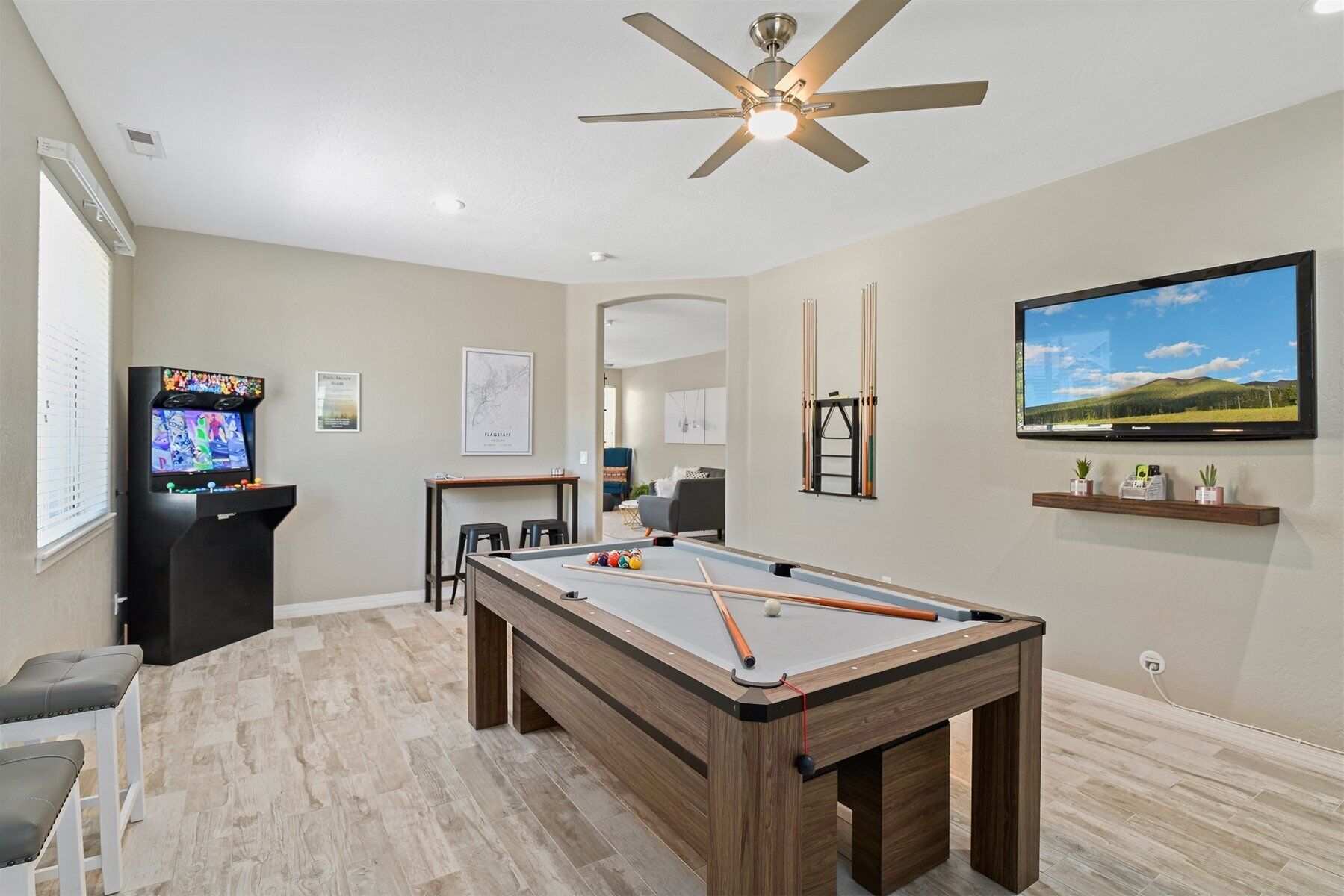 Une table de billard dans une pièce dotée d’un ventilateur de plafond, d’un téléviseur et d’un tableau encadré au mur.
