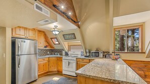 Una cucina con mobili in legno, un frigorifero in acciaio inossidabile, un fornello e un piano di lavoro in granito.