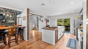 Una cocina amplia con una isla central, suelo de madera y un muro decorativo de piedra.