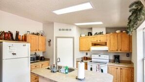 A compact kitchen with wooden cabinets, a refrigerator, a microwave, a stove, and a sink.