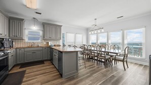 Une cuisine moderne avec des meubles gris, un grand îlot central et un coin repas offrant une vue agréable.