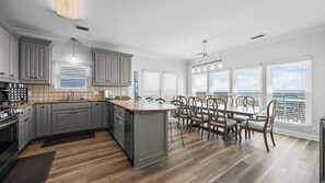 Une cuisine moderne avec des meubles gris, un grand îlot central et un coin repas offrant une vue agréable.