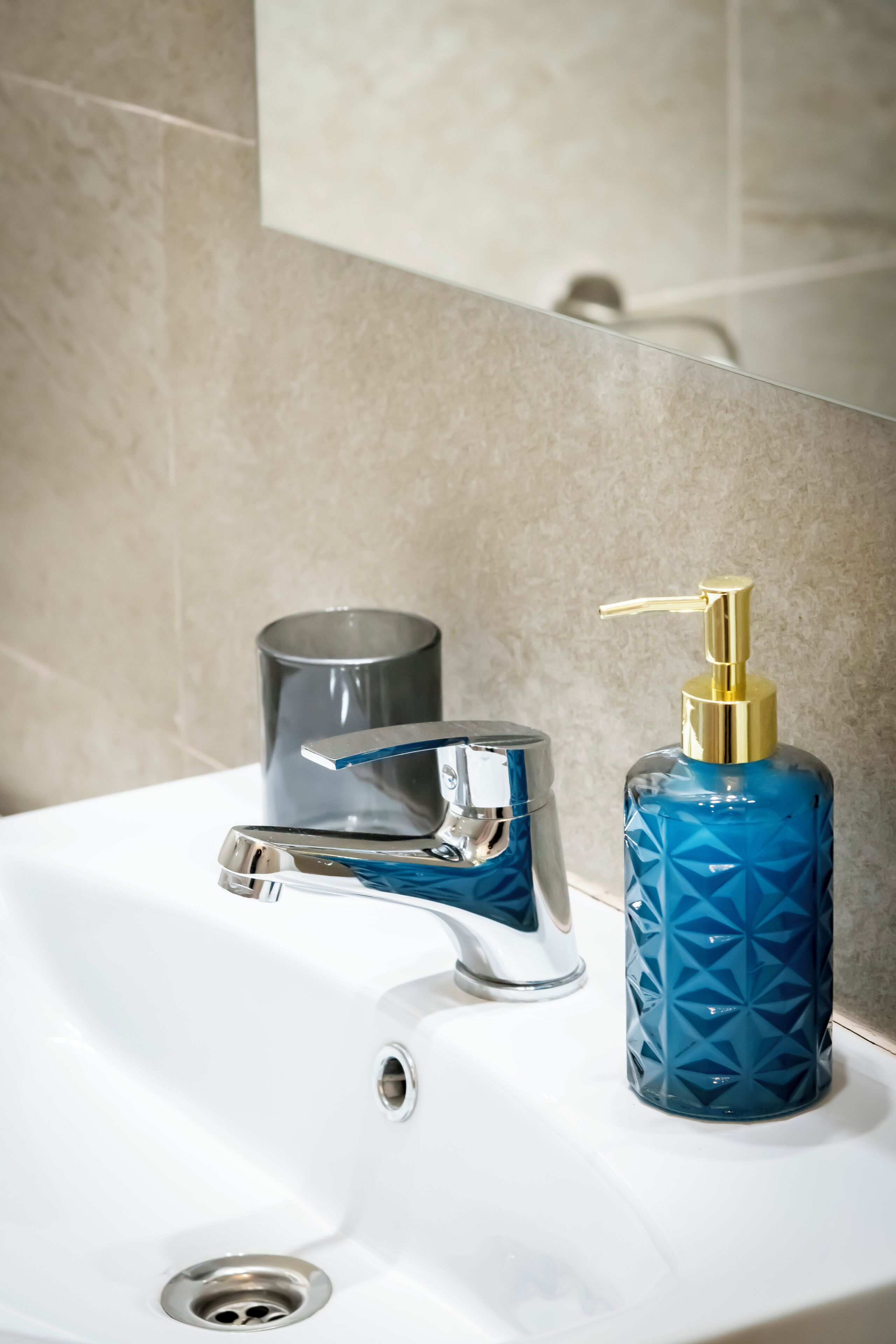 A bathroom sink with a modern faucet and a blue soap dispenser.