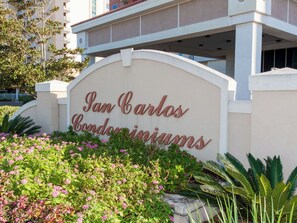 A sign for 'San Carlos Condominiums' with a landscaped area in front.