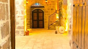 An arched stone doorway leading to a courtyard with a stone wall, a wooden door, and a small staircase. - Sultan Konagi Hotel (Mardin)