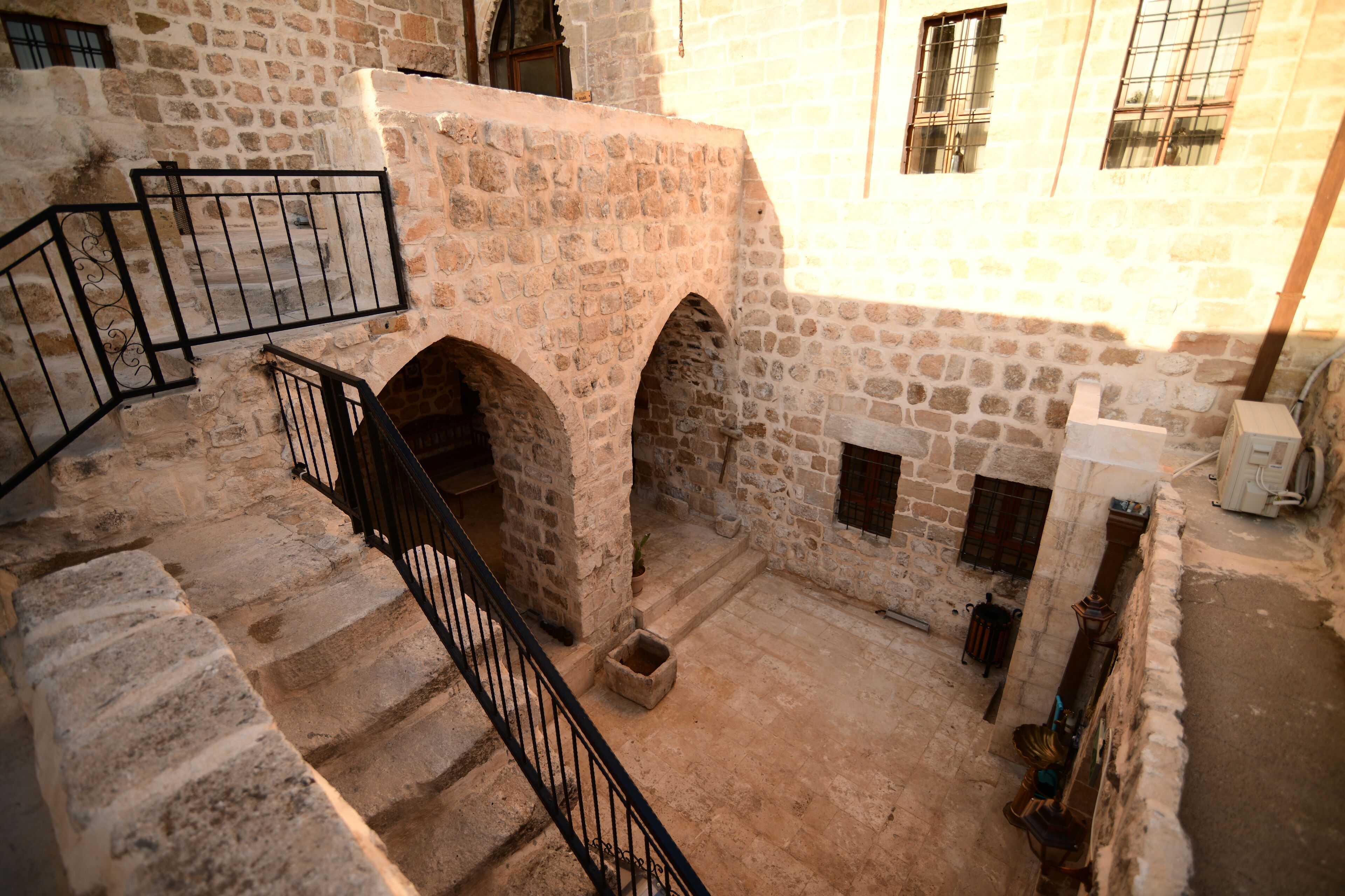 Una escalera de piedra que conduce a un nivel superior con aberturas en arco y un pequeño patio.