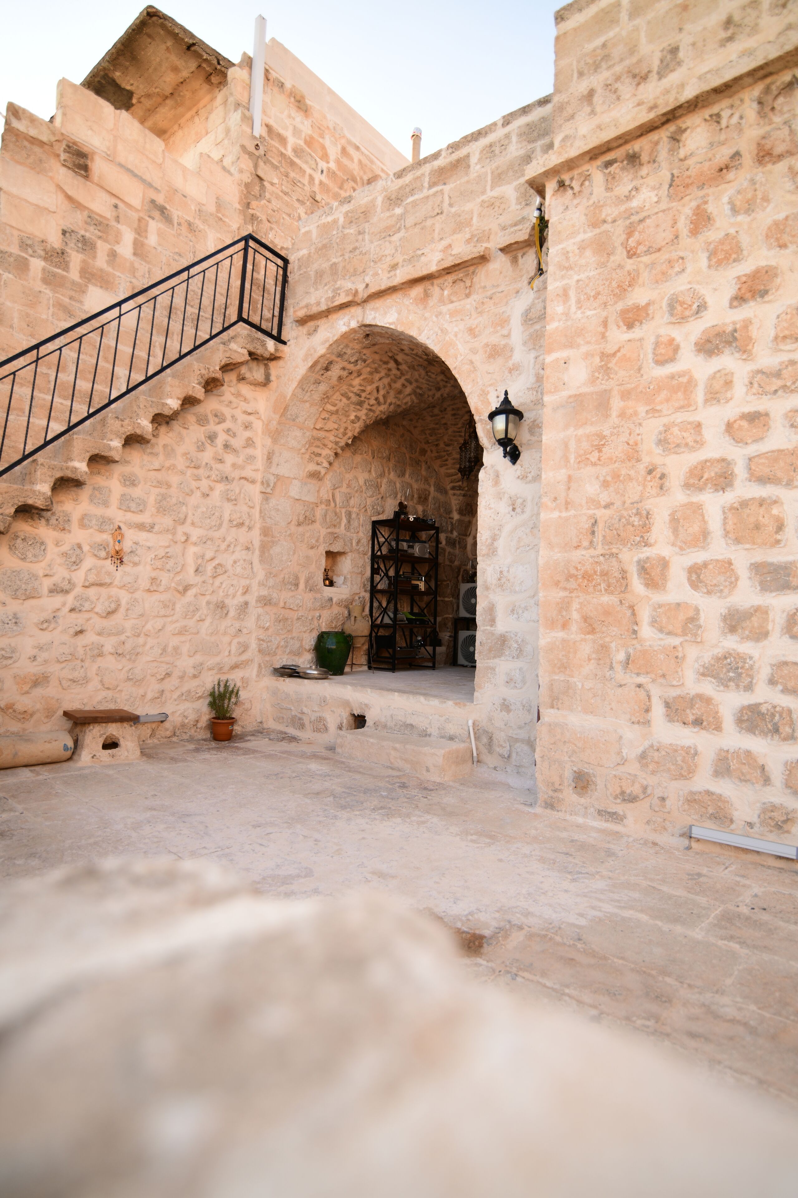 A stone building with a staircase leading to an arched doorway.
