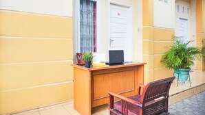 A reception desk with a laptop, a potted plant, and a wooden chair. - Hotel O Tanjung Karang Near Central Plaza Formerly Wisma Bambu (Bandar Lampung)