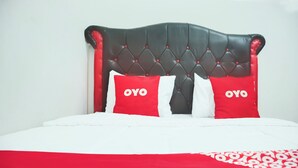 A bed with a black headboard, two red pillows with "OYO" text, and a white bedspread. - Hotel O Tanjung Karang Near Central Plaza Formerly Wisma Bambu (Bandar Lampung)