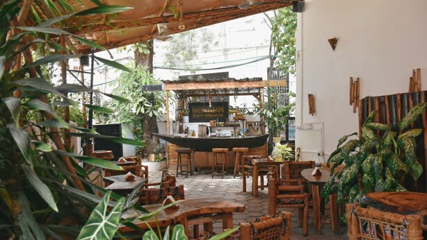 An outdoor cafe with wooden furniture and a central bar area.
