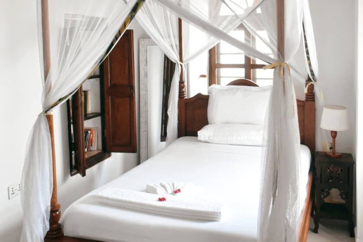 A four-poster bed with a canopy, a bedside table with a lamp, and a nightstand with a lamp.