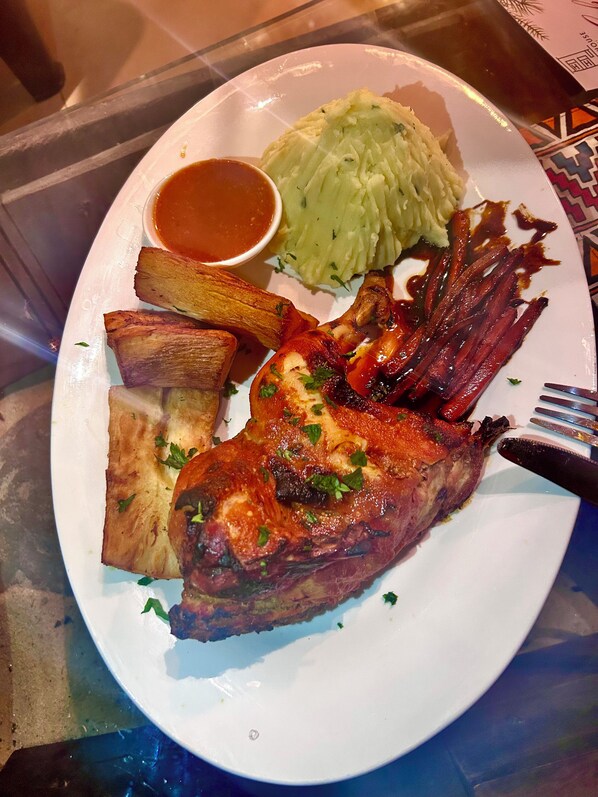 A plate with roasted meat, mashed potatoes, and a side of gravy. - Habari House (Zanzibar Town)