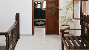 A hallway with a wooden door, a bench, and a potted plant.