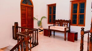 A staircase with wooden railings, a bench, and two windows with wooden frames.