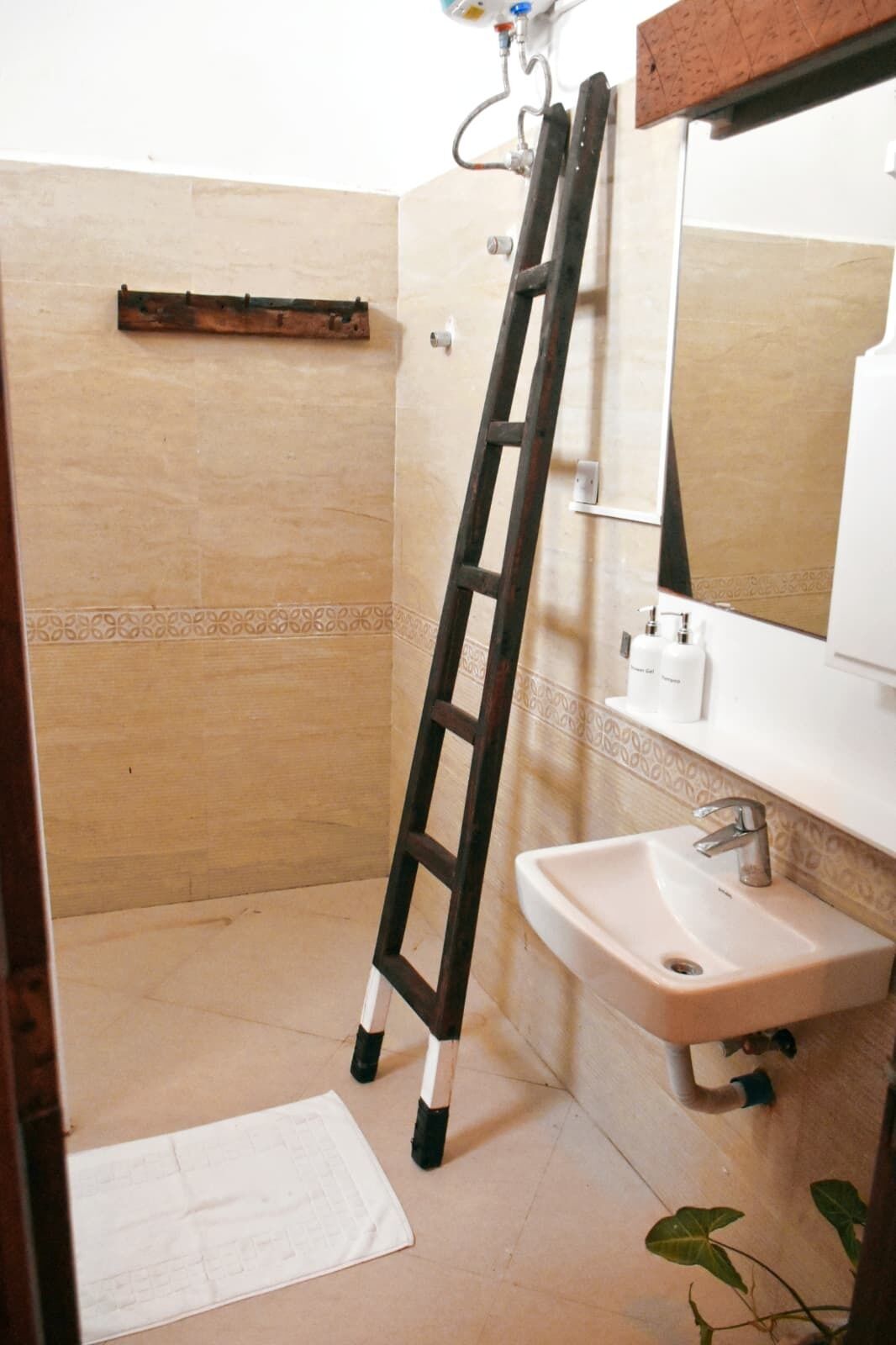 A bathroom with a white sink, a mirror, and a wooden shelf.