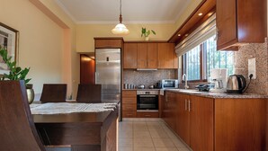 A modern kitchen with wooden cabinets, stainless steel appliances, and a dining area with a table and chairs.