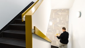 Eine moderne Treppe mit schwarzer Handlauf und gelbem Akzent.