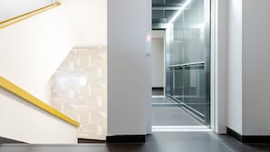 Ein moderner Aufzug mit digitaler Anzeige, Glastür und Wand mit geometrischem Muster.
