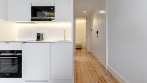 Een moderne keuken met witte kastjes, een inbouwoven en een magnetron.