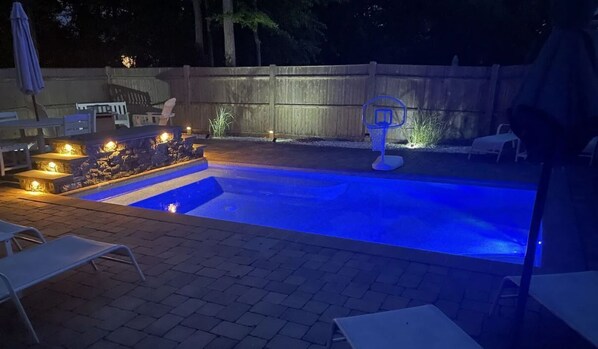 Relax in a serene outdoor space with a pool, lounge chairs, and a table for unwinding.